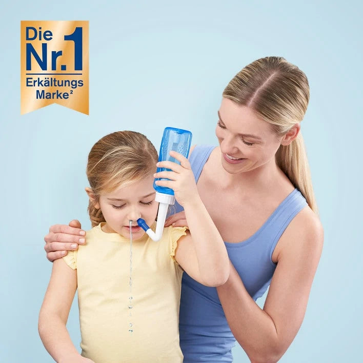 Eine Frau hilft einem Mädchen bei der Anwendung eines Nasenspülgeräts, wobei Wasser aus der Nase des Mädchens fließt.