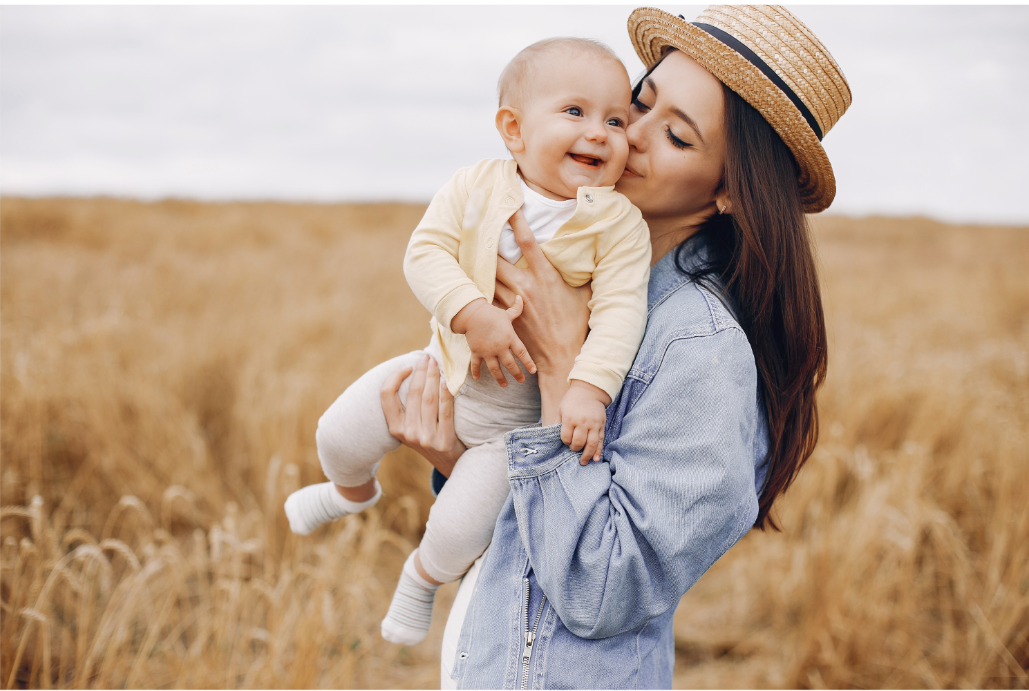 Eine junge Frau in der Natur hält ein glückliches Baby im Arm